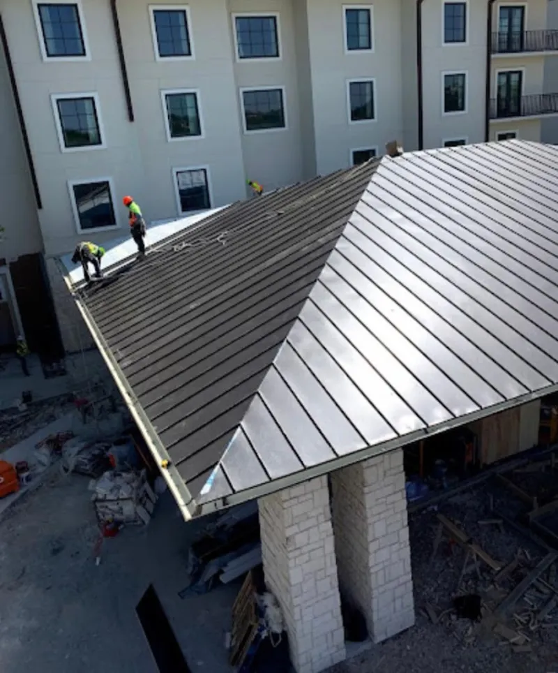 Crew installing standing seam metal roof panels on a commercial project in Linton Hall